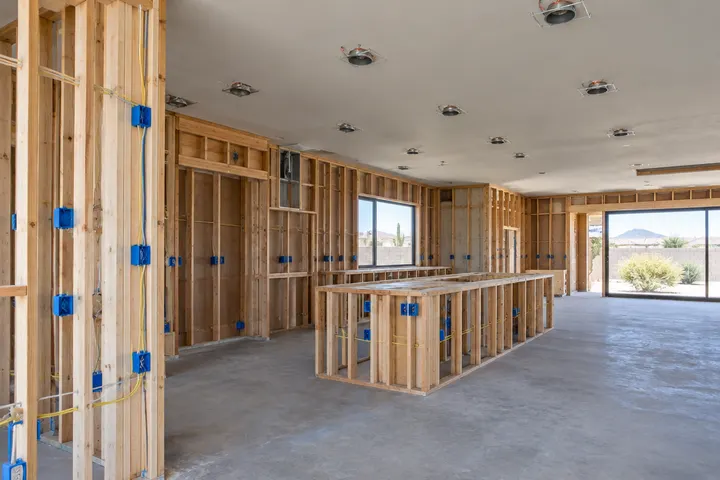 Electrician-installed outlet boxes and recessed light cans in open kitchen walls and ceiling before drywall